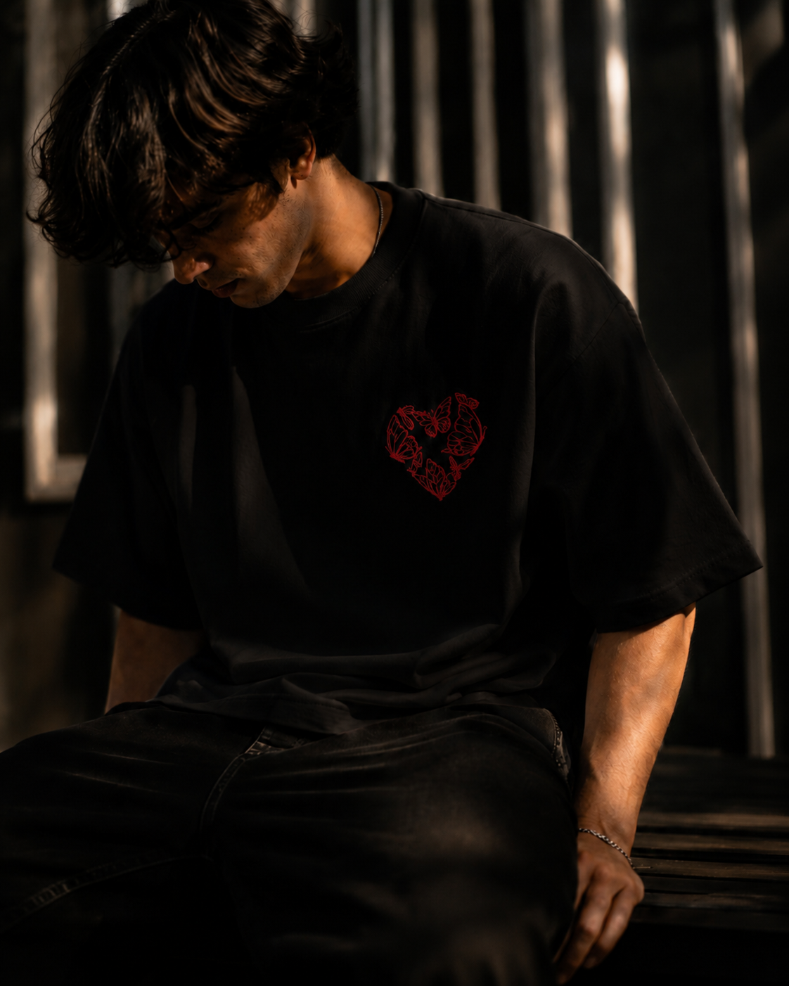 Person wearing a black t-shirt with a red logo in a dimly lit setting