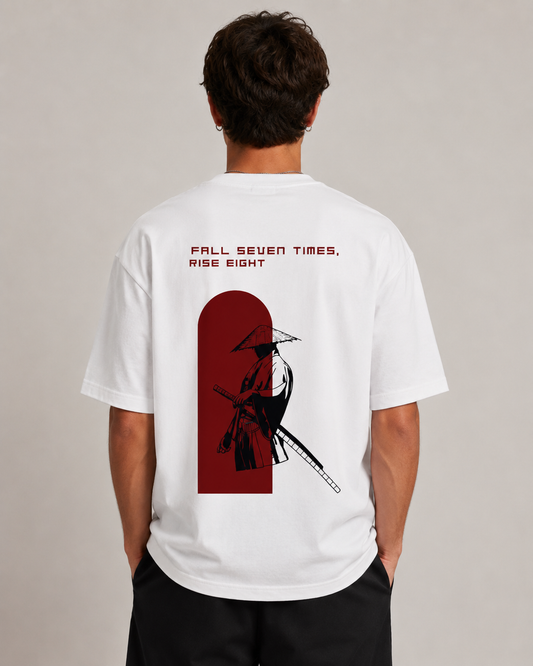 Back view of a white T-shirt featuring the phrase ‘FALL SEVEN TIMES, RISE EIGHT’ and a red silhouette of a warrior holding a sword and rifle-like weapon.