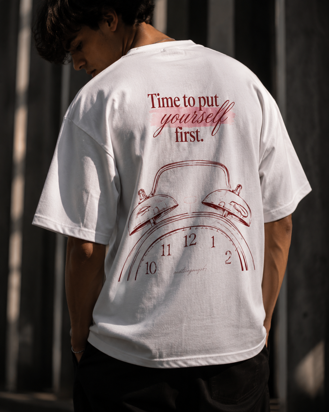Person wearing a white t-shirt with a red graphic and text on the back.